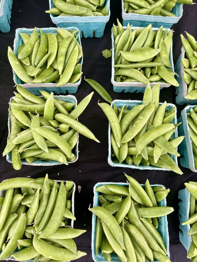 Baskets of fresh snap peas at a produce stand