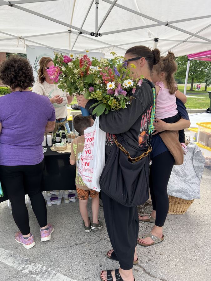Shoppers browsing flower stands under market tents